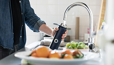 Person filling water bottle from tap